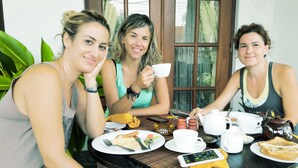 Three people sitting at a table with plates of food, cups, and a teapot. - The Terranova Inn (Negombo)