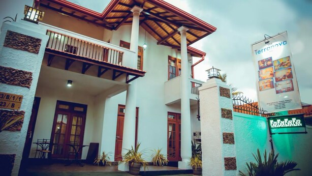 A two-story building with a balcony, a signboard, and a green gate. - The Terranova Inn (Negombo)