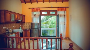 A kitchen with wooden cabinets, a washing machine, and a balcony with curtains. - The Terranova Inn (Negombo)