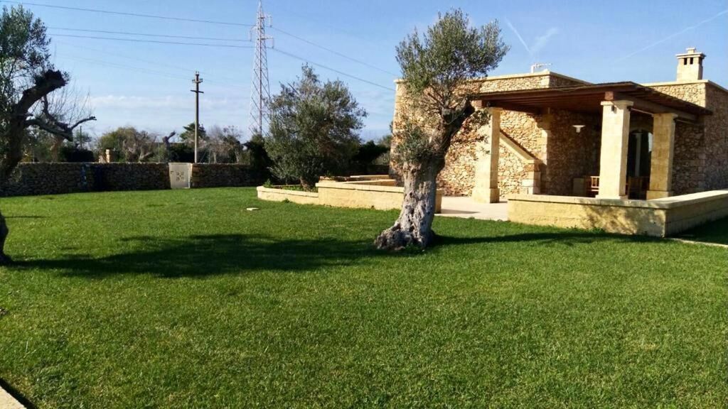 A stone house with a covered patio and a well-maintained lawn.