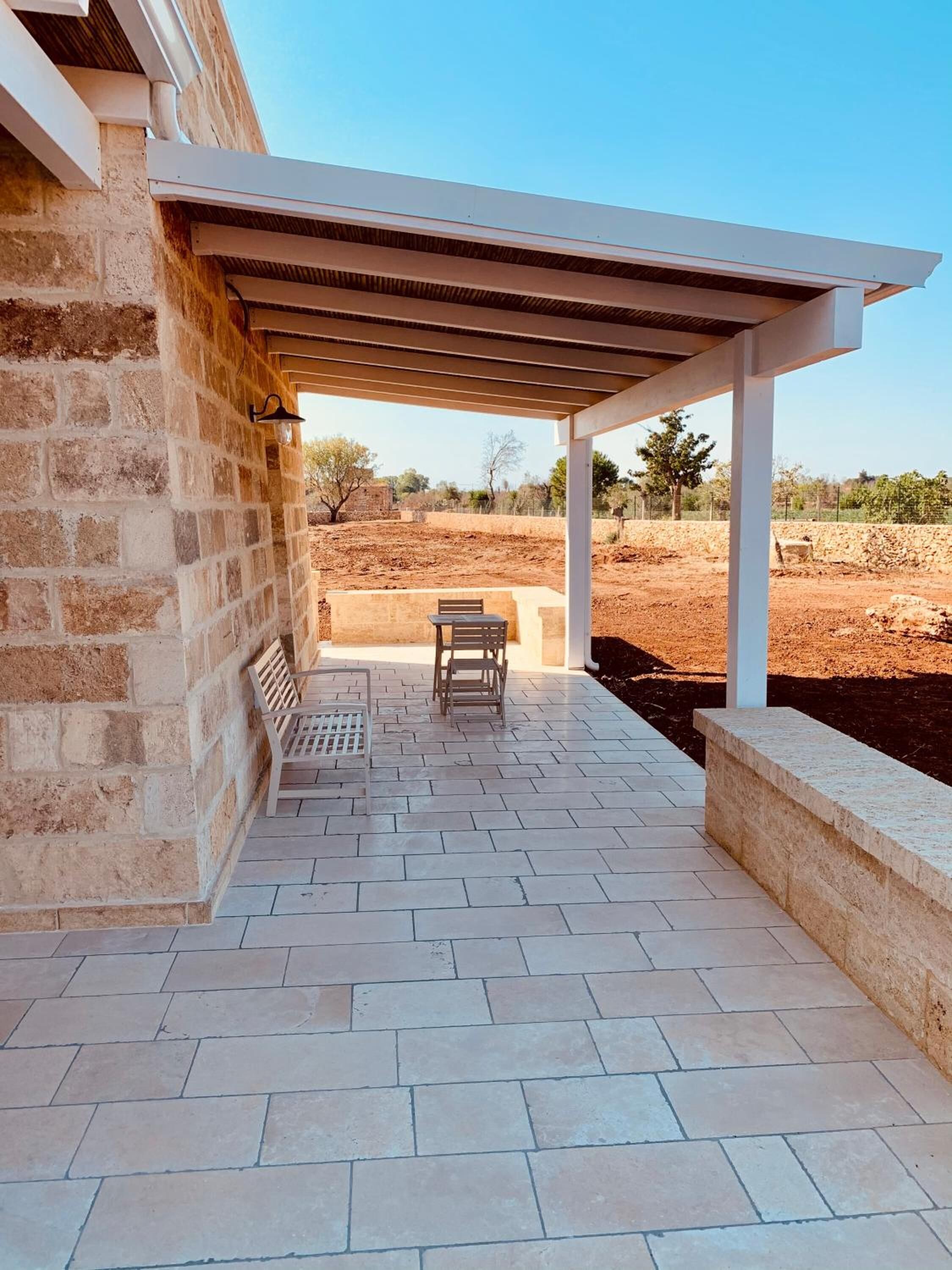 A covered patio area with a brick wall, a pergola, and a table with chairs.