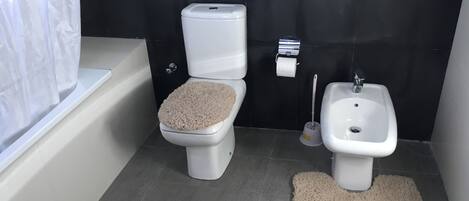 Un baño con inodoro, bidé y bañera.