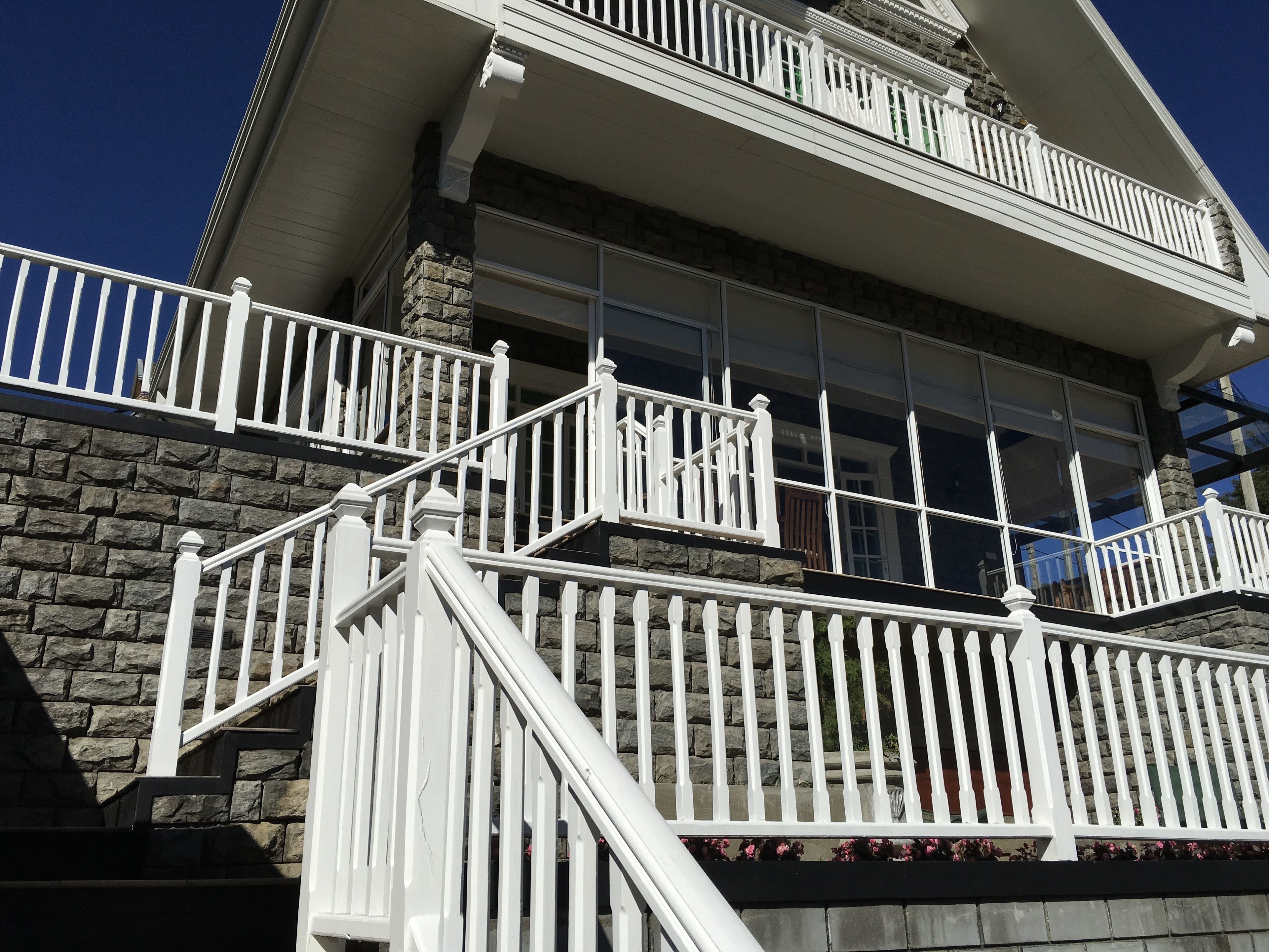 A multi-story building with white railings and stone facade.