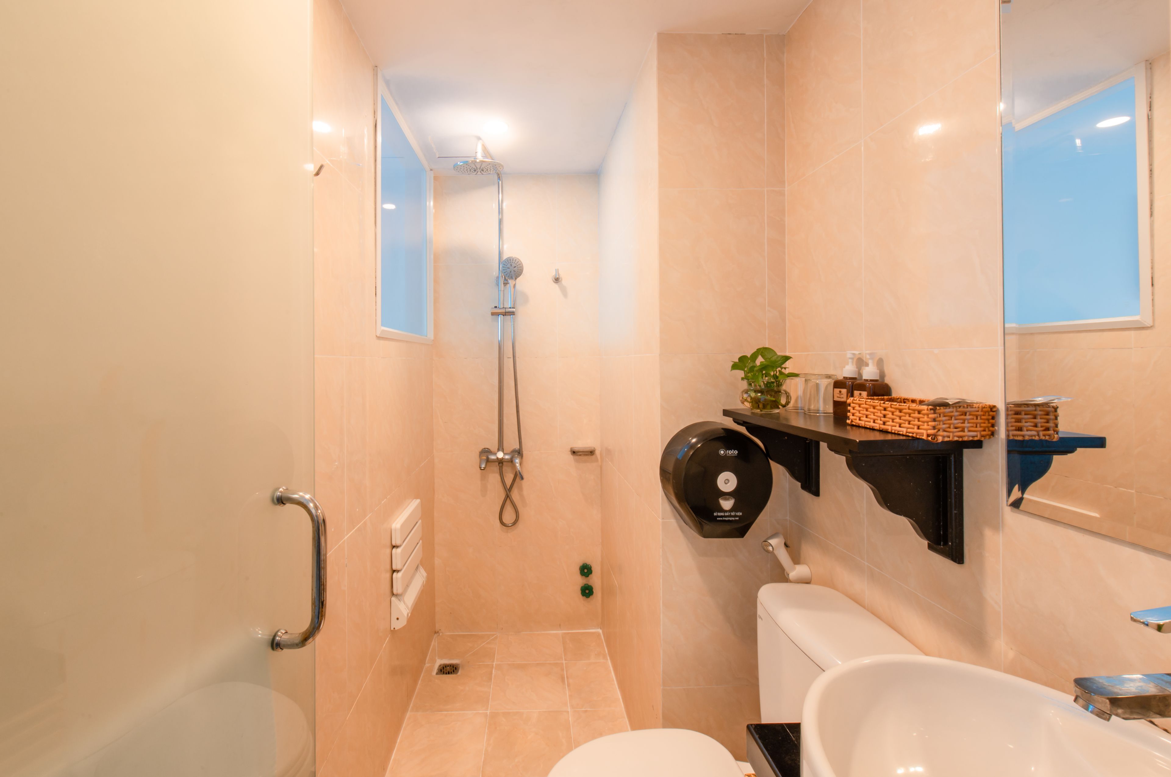 Une salle de bain équipée d’une douche, de toilettes et d’une étagère où sont rangés les articles de toilette.