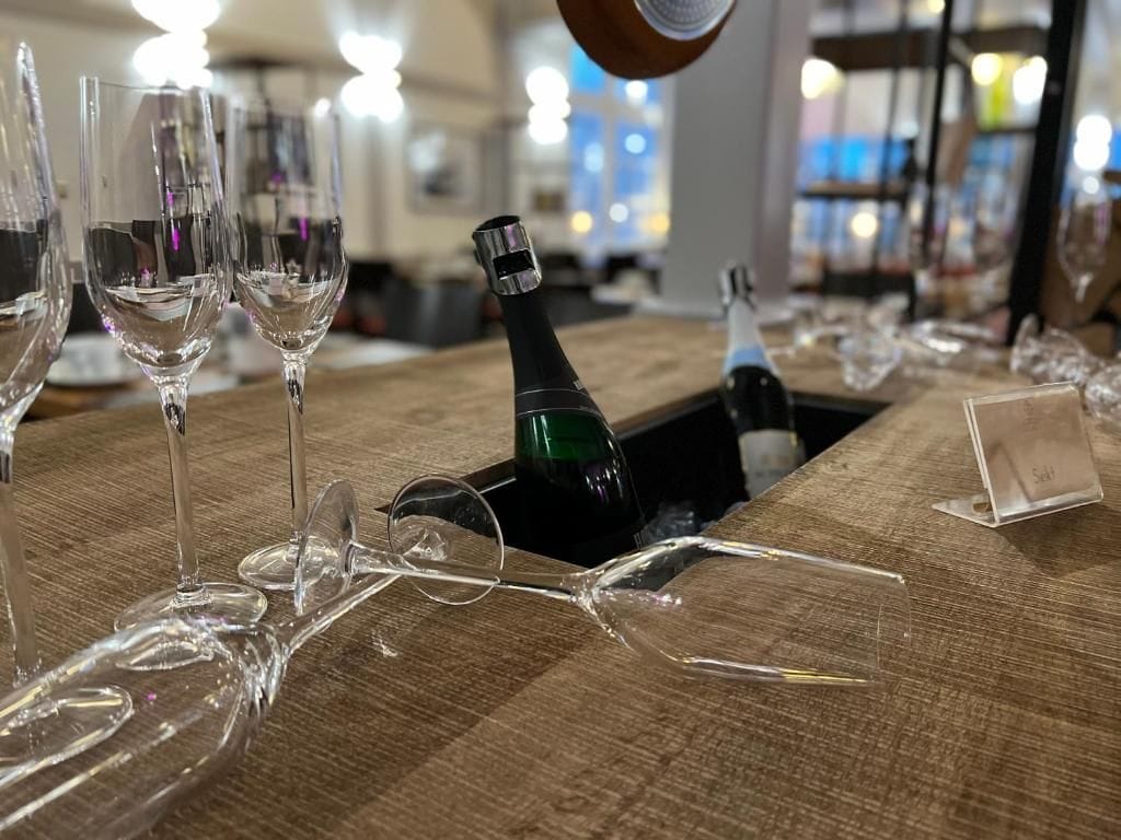 Een bar met glazen en een fles op een houten tafel.