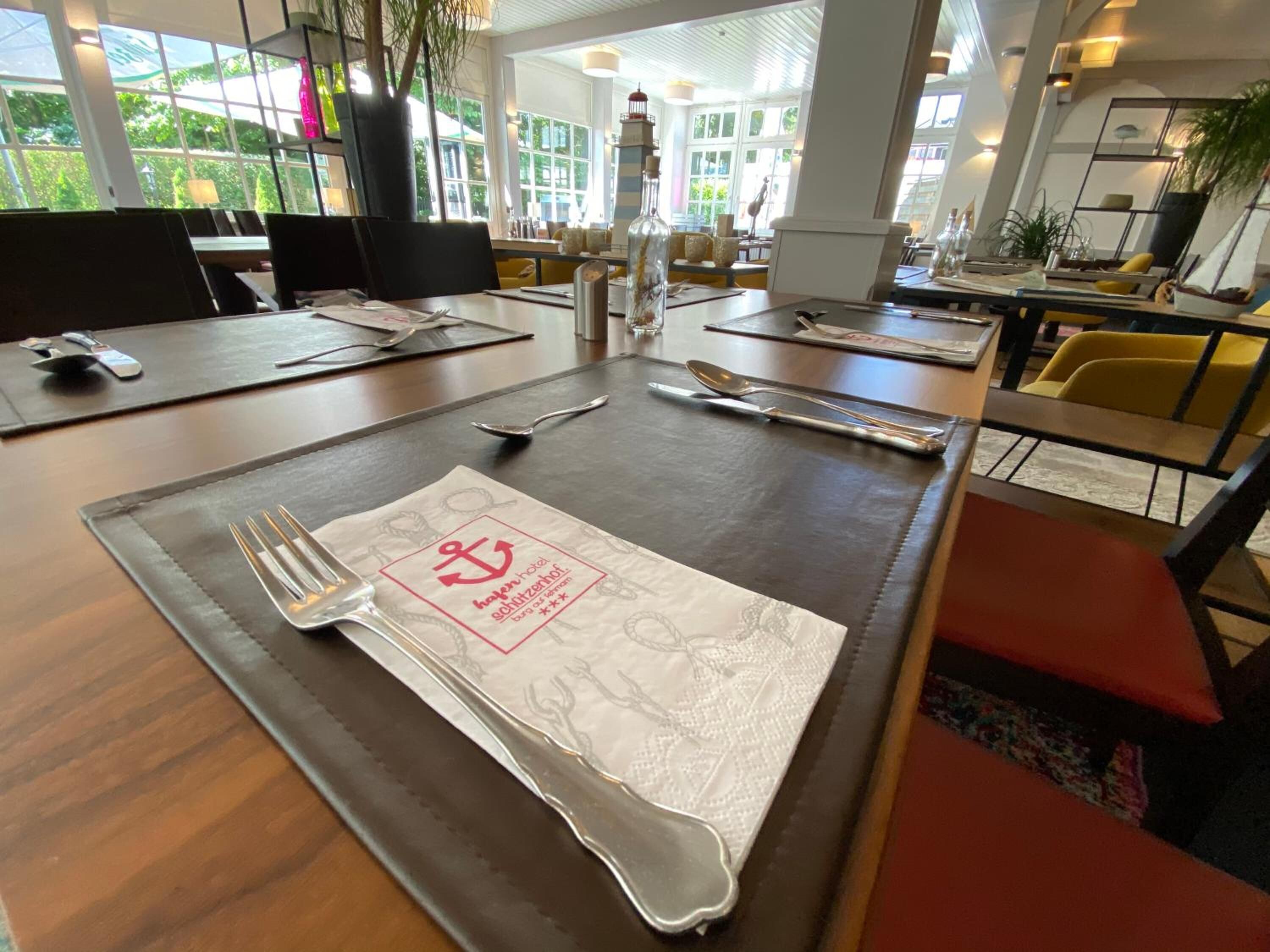 A restaurant setting with tables set for dining, including cutlery and napkins.