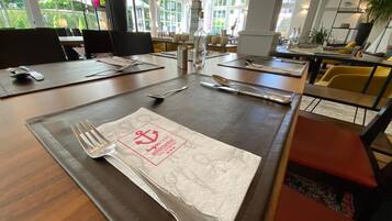 A restaurant setting with tables set for dining, including cutlery and napkins.