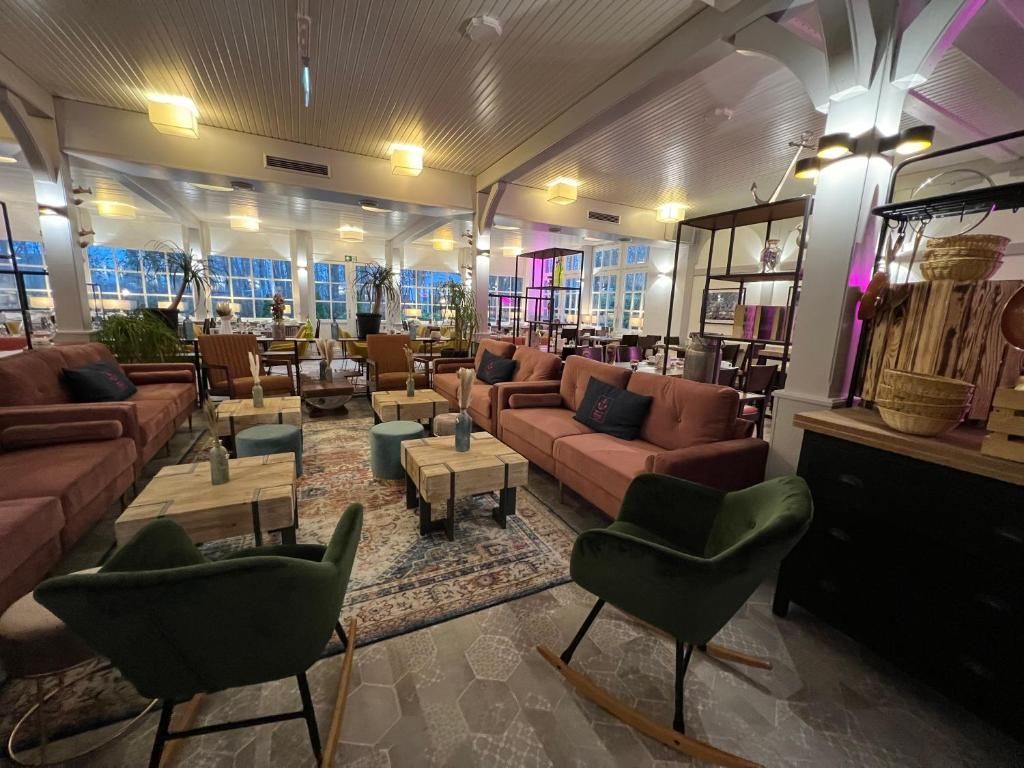 Un vaste espace salon offrant de nombreuses options d’assises, notamment des canapés et des fauteuils, une table basse et un tapis à motifs.