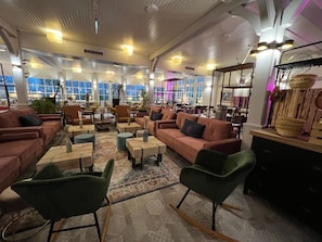 A spacious lounge area with multiple seating options including sofas and chairs, a coffee table, and a patterned rug. - Hafen Hotel Schützenhof (Fehmarn)