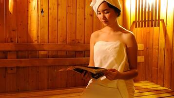 A person sitting on a wooden bench in a sauna with wooden walls and benches.