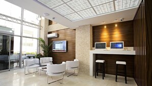 Uma área de recepção moderna com parede de vidro, mobiliário branco e parede de destaque em madeira.