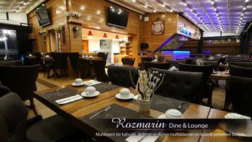 A cozy restaurant with wooden decor and comfortable seating. Tables are set with white plates and silverware.