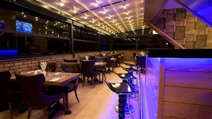 Restaurante com parede de tijolos, mesas e cadeiras de madeira.