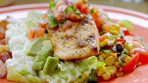 A plate with grilled fish, avocado, lettuce, and a colorful vegetable salad. - End Glory Hotel (Corlu)