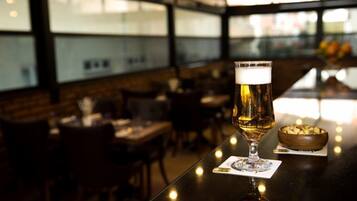 Eine Bar mit einem Bierglas auf einem Untersetzer, einer Schüssel Nüssen und einer Speisekarte auf dem Tisch.