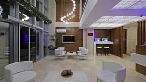 Um lobby moderno com balcão de recepção, área de estar e uma janela grande.