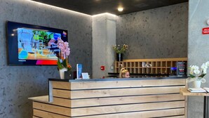 Un comptoir d’accueil avec un téléviseur à écran plat fixé au mur, un lambris en bois et un vase rempli de fleurs.