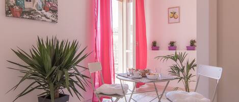 Una habitación con una mesa de comedor, sillas, plantas en macetas y un cuadro en la pared.