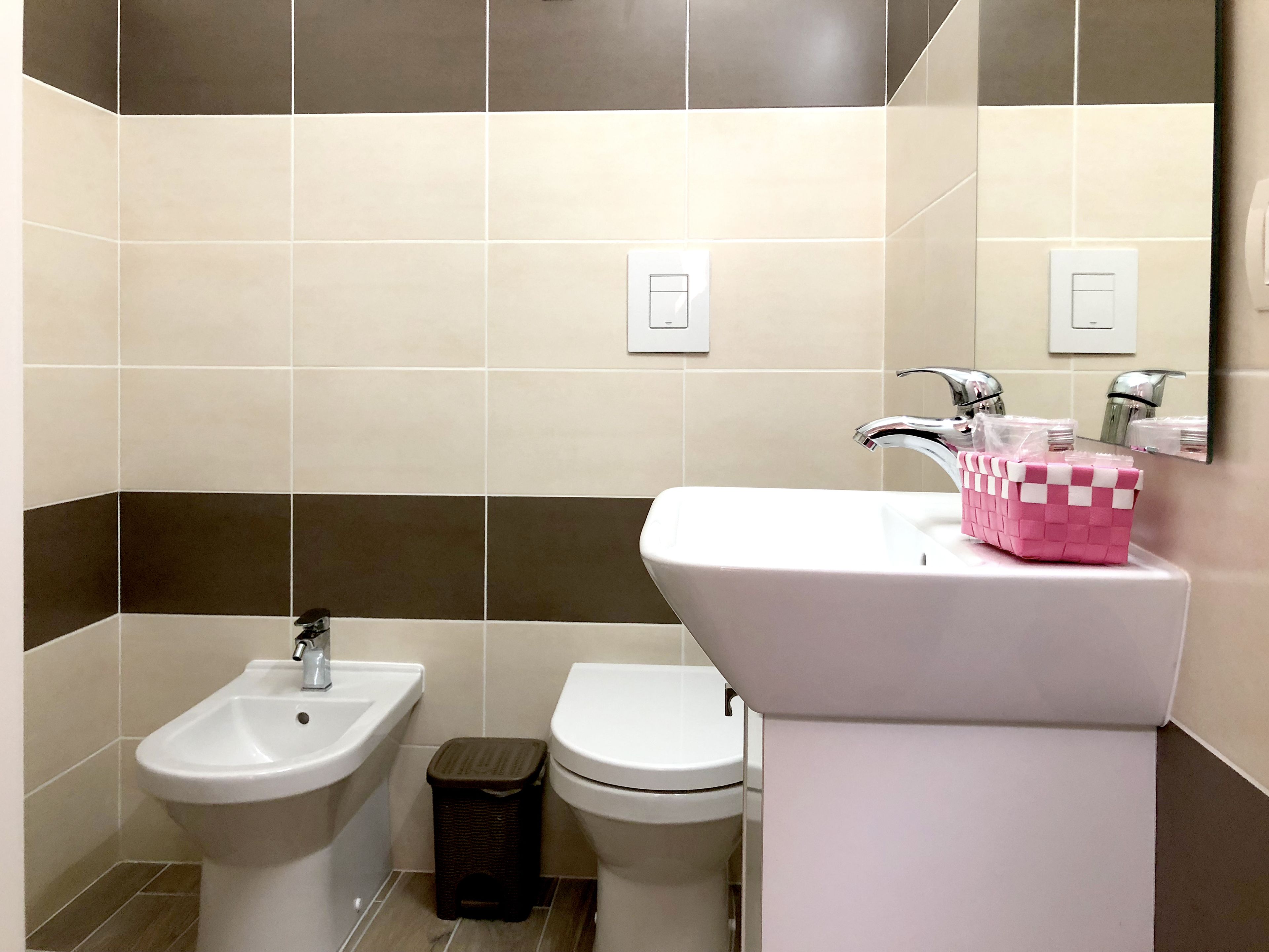 A bathroom with a bidet, toilet, and sink.