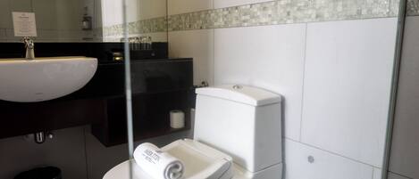 Un baño moderno con lavamanos, inodoro y mampara de vidrio.