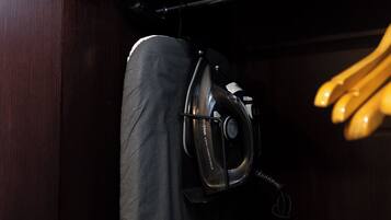 A compact, dark-colored closet with a hanging garment and a black iron appliance.
