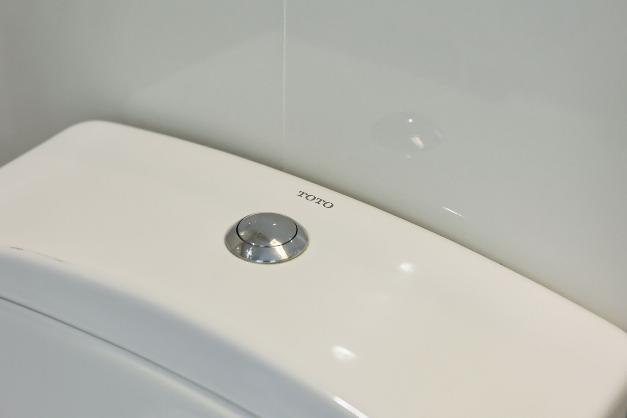 A white toilet with a Toto brand label and a flush handle.