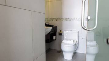 A bathroom with two toilets, a sink, and a mirror.