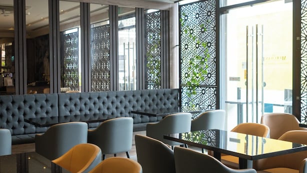 A modern interior with a seating area, tables, and a view through large windows. - Meritin Hotel (Kuching)