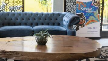 A blue sofa, a wooden coffee table with a plant, and a poster in the background.