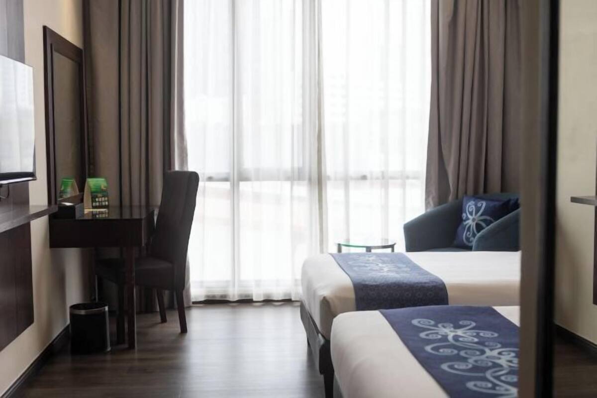 A hotel room with a bed, a desk, a chair, and a TV.