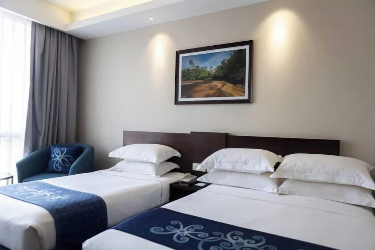 Una habitación de hotel con dos camas, una mesita de noche, una silla y un cuadro en la pared.