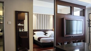 A hotel room with a bed, a television, a mirror, and a wooden floor. - Meritin Hotel (Kuching)