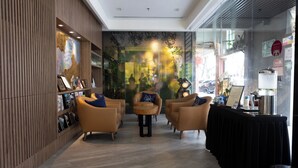 A lobby with a reception desk, seating area, and a wall with artwork. - Meritin Hotel (Kuching)
