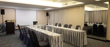A conference room with a long table, chairs, a podium, and a projection screen.