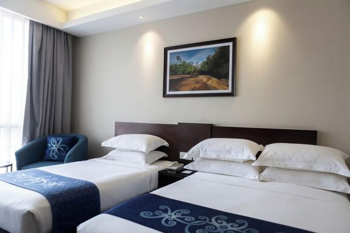 A hotel room with two beds, a nightstand, a chair, and a painting on the wall.
