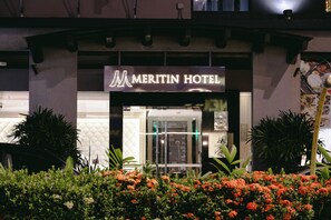 The exterior of the Meritin Hotel with a modern facade, a prominent entrance, and surrounding greenery. - Meritin Hotel (Kuching)