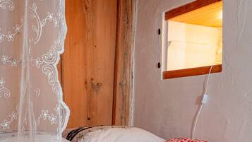 Ein Schlafzimmer mit Holztür, einem Fenster mit Holzrahmen und einem Bett mit karierter Bettwäsche.