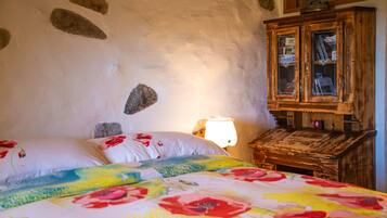 A bedroom with a bed, a wooden cabinet, and a lamp.