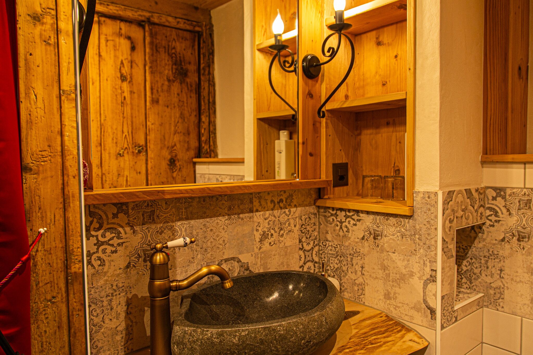 A bathroom with a stone sink, wooden cabinets, and patterned tiles.