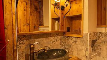 A bathroom with a stone sink, wooden cabinets, and patterned tiles.