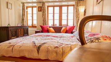 Ein Schlafzimmer mit einem Bett, einem hölzernen Kopfteil, einer Kommode und einem Fenster mit Vorhängen.