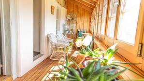 Una habitación con paneles de madera, sillas de mimbre, una pequeña mesa y plantas en macetas.