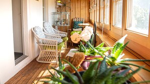Una habitación iluminada por el sol con sillas de mimbre, una mesa con sillas y suelo de madera.