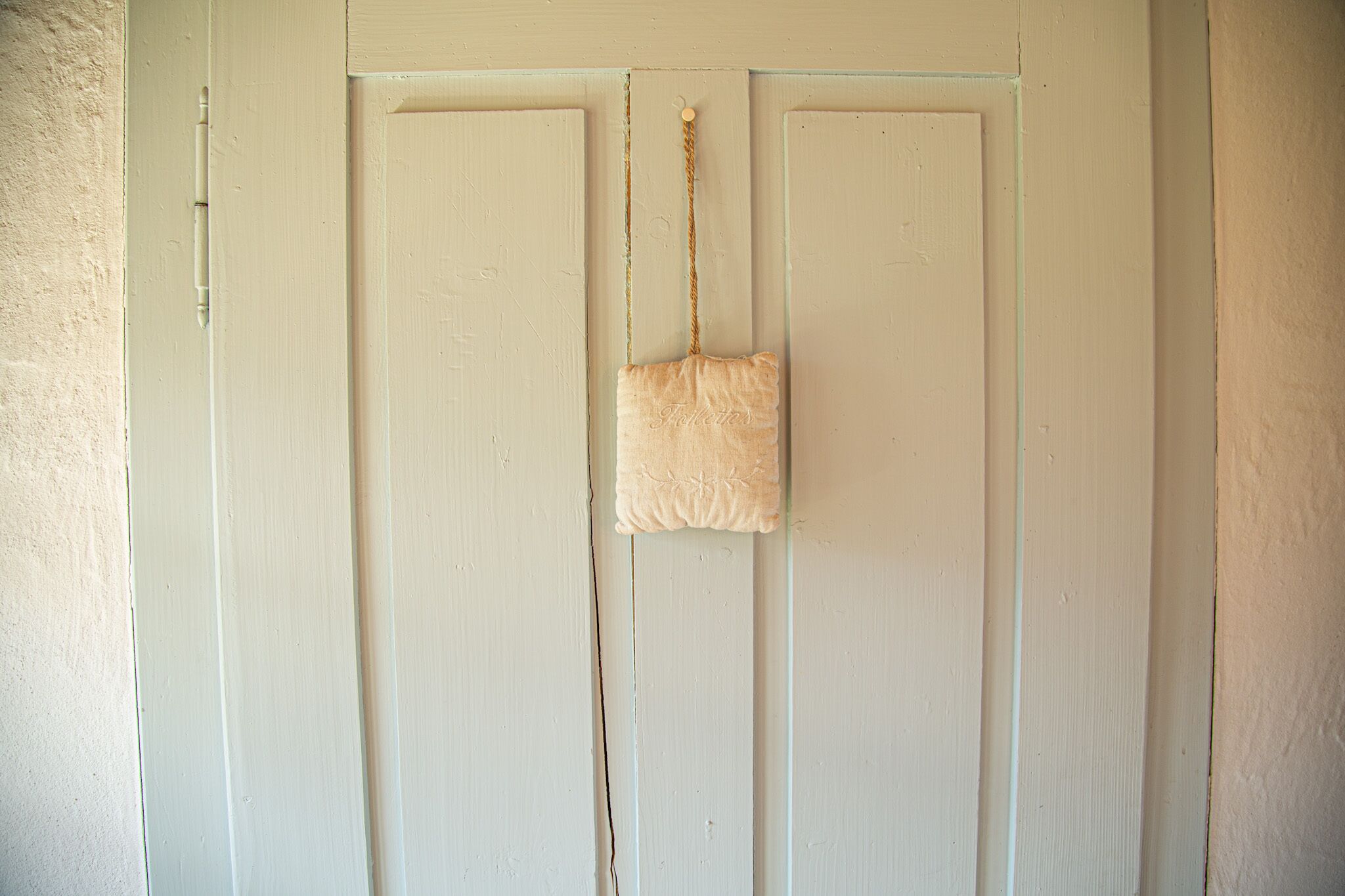 A white door with a small beige bag hanging on a rope.