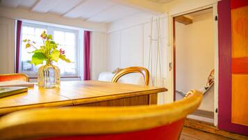 Een eetgedeelte met een houten tafel, een vaas met bloemen en een rode stoel.