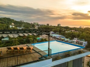 A rooftop pool with lounge chairs, a view of the sea, and surrounding buildings. - Golden Daisy Hotel (Phu Quoc)