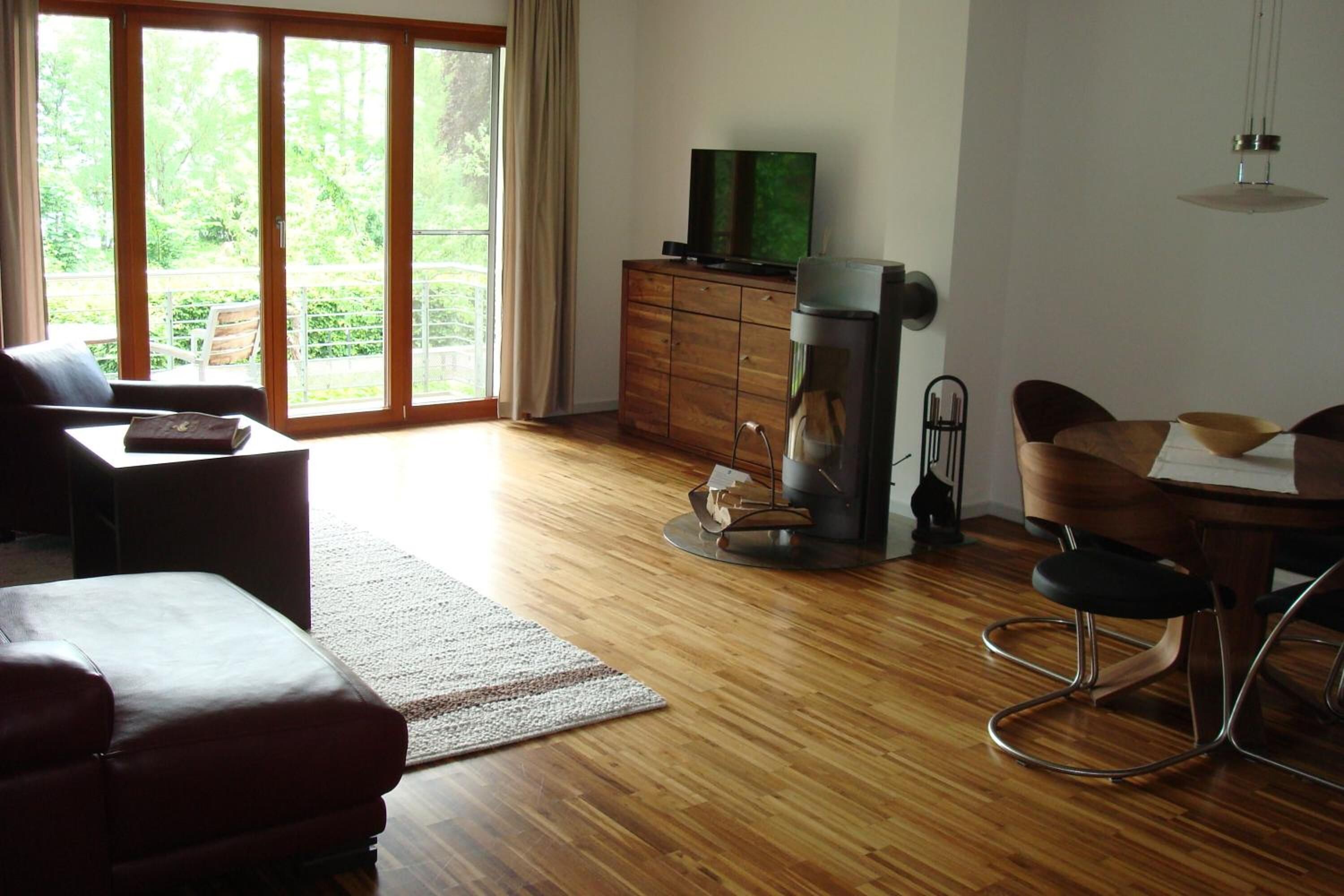 A living room with a sofa, a coffee table, a TV on a wooden cabinet, a coffee machine, and a dining area with a table and chairs.