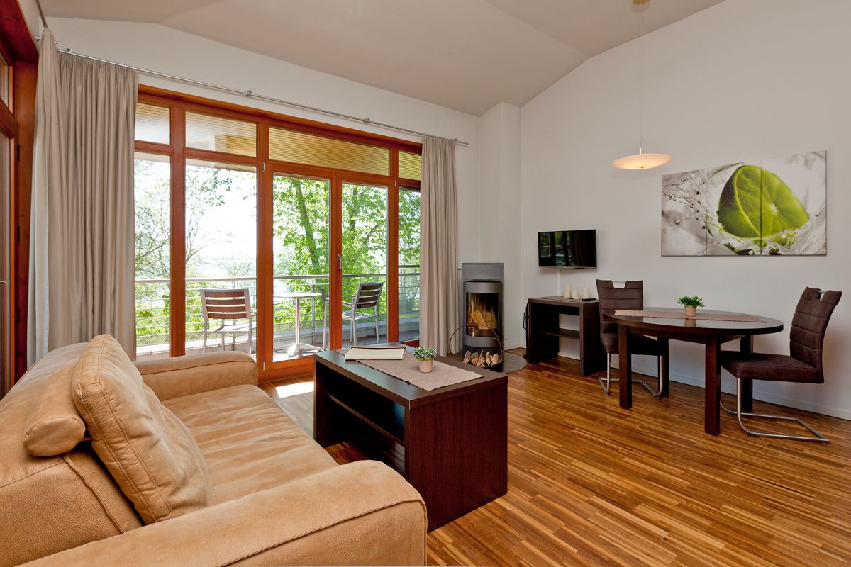 Una sala de estar moderna con un sofá, chimenea, mesa de comedor con sillas y televisor montado en la pared.