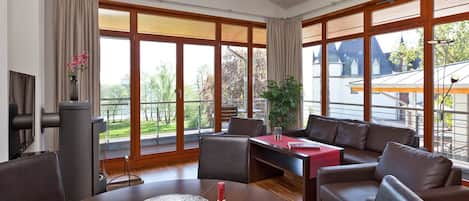 Una sala moderna con una mesa de comedor, sofás de cuero y ventanas amplias que ofrecen vistas al exterior.