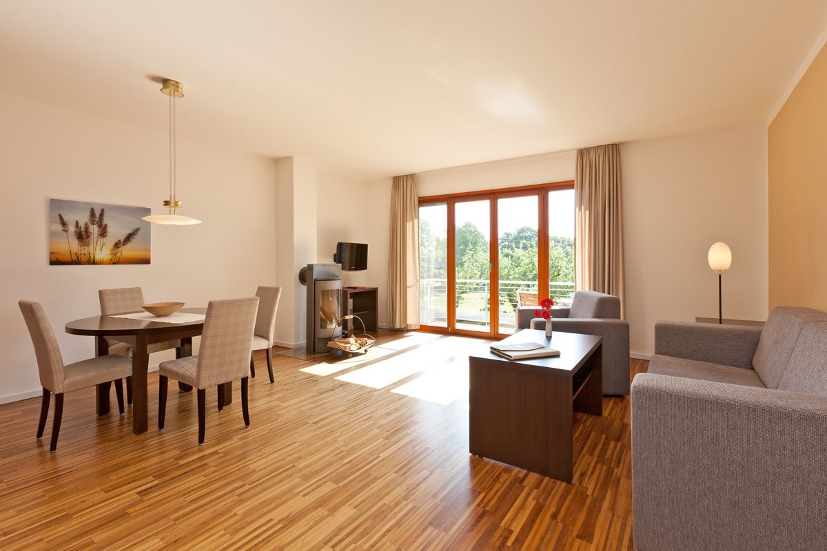 Ein modernes Wohnzimmer mit Holzboden, einem Esstisch mit Stühlen, einer Couch, einem Fernseher und einem Kamin.